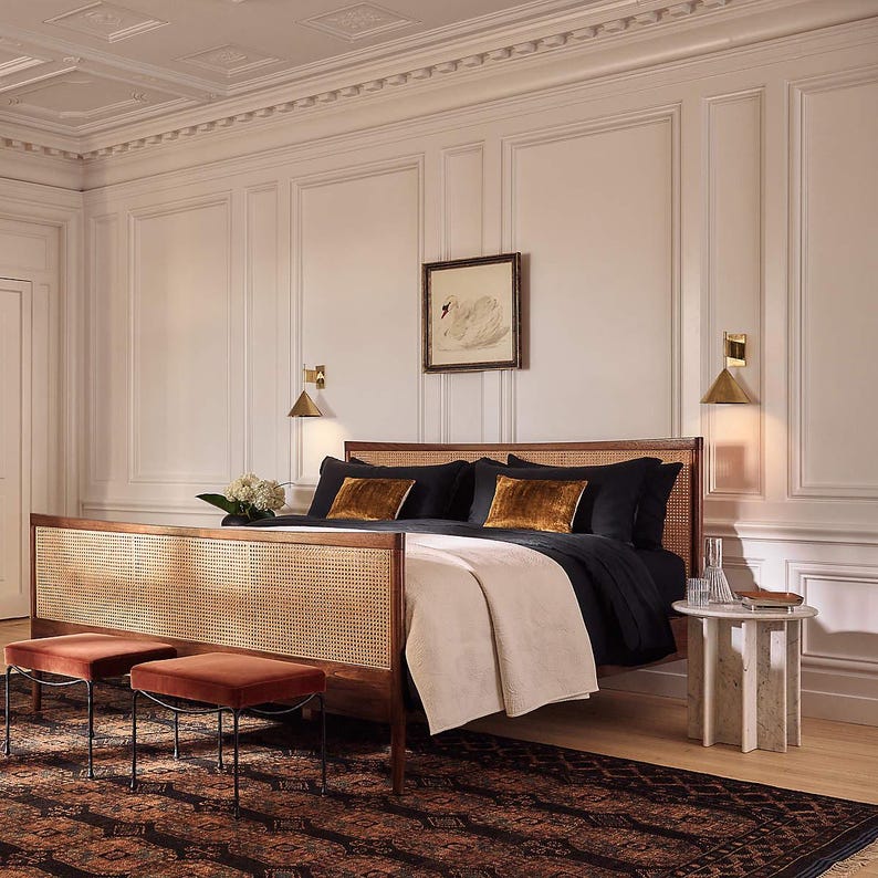 Luxurious bedroom with a wooden bed, black and gold bedding, and decorative handmade rug.