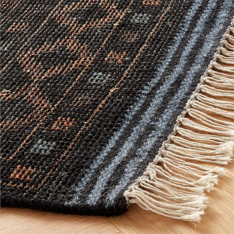 Textured rug with geometric pattern and fringed edge on wooden floor