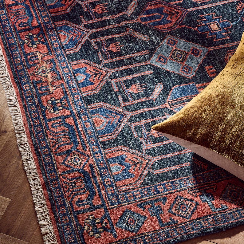 Decorative hand knotted oushak rug with intricate patterns on a wooden floor, featuring a gold pillow.